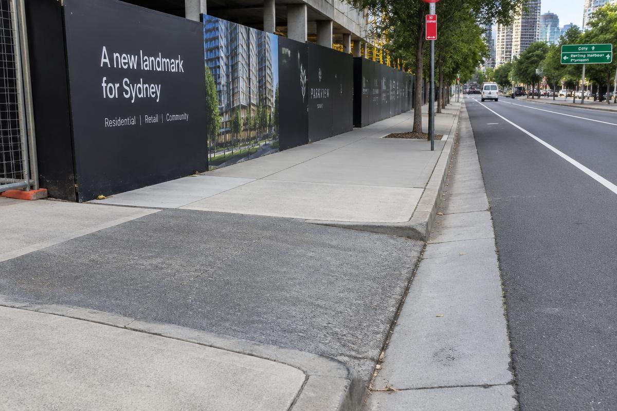 Footpath, kerb and road beside a construction hoarding (illustrative image)